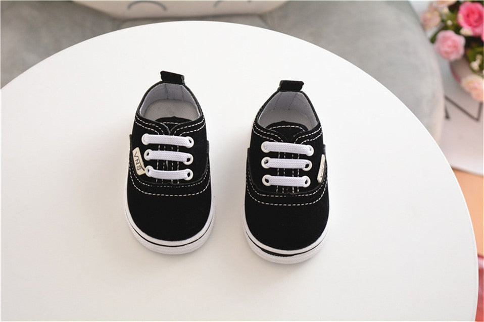 zapatos de vestir Vans de color negro sobre mesa blanca de frente