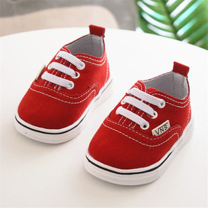 zapato de color rojo para vestir de bebe Vans sobre mesa blanca