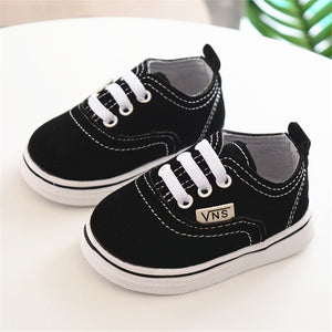 zapatos de bebe Vans para vestir de color negro sobre mesa blanca de lado